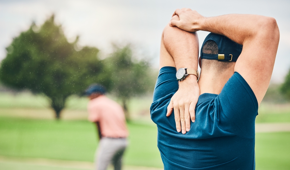 A man stretching his arms before golfing.