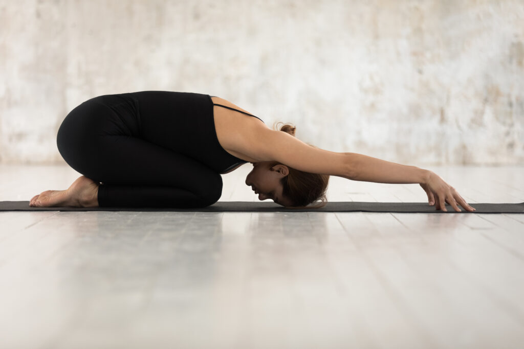 A woman in black athleisure, practicing the Child's pose for lower back pain