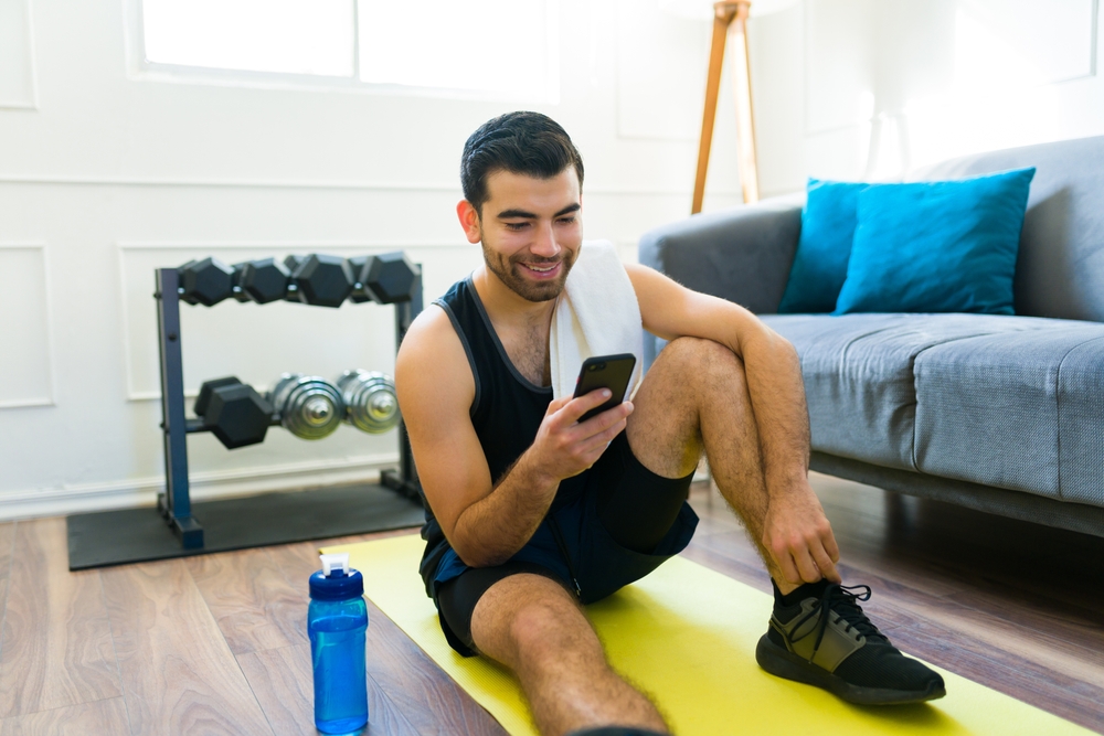 the golfer, still at home, on his phone getting ready to call a physical therapist for help with his golf game 