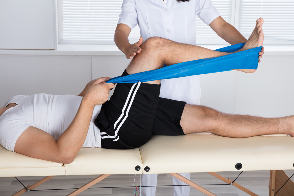 A physiotherapist helping a patient stretch his leg.